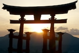 the sun sets over a mountain behind a torri gate in Miyajima