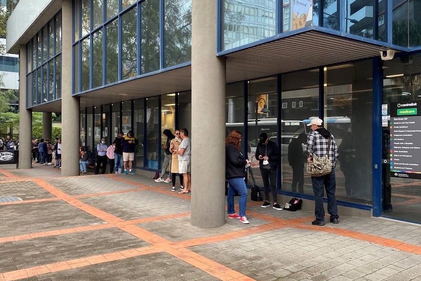 People are lining up outside the office windows, and the line appears to stretch around the building.