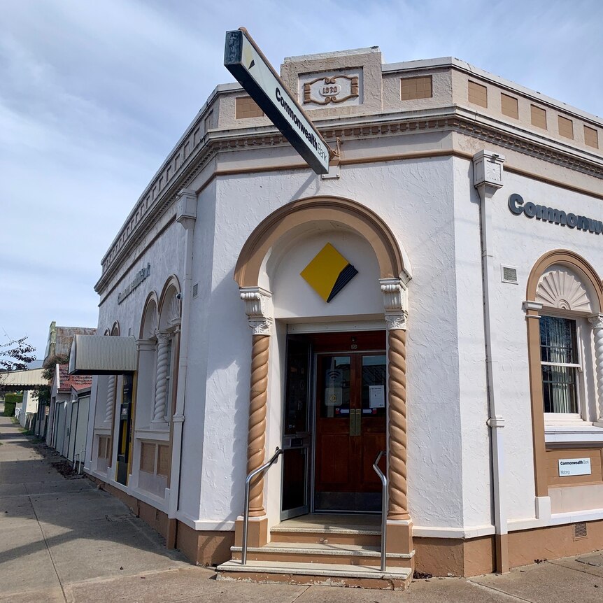 Image of a Commonwealth Bank branch, a historic building, which sits on the corner of a street, with a white fascade