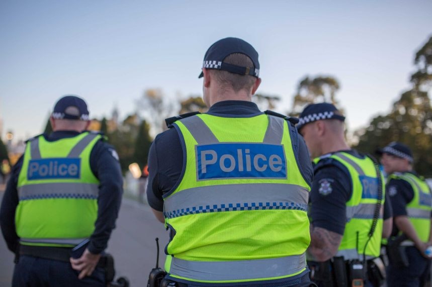 Four police in uniform face backs to camera on street