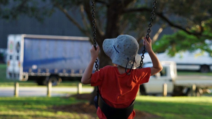 Anonymous child on a swing in a park.