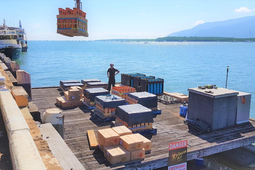 pallets of fireworks being loaded by crane onto a wharf