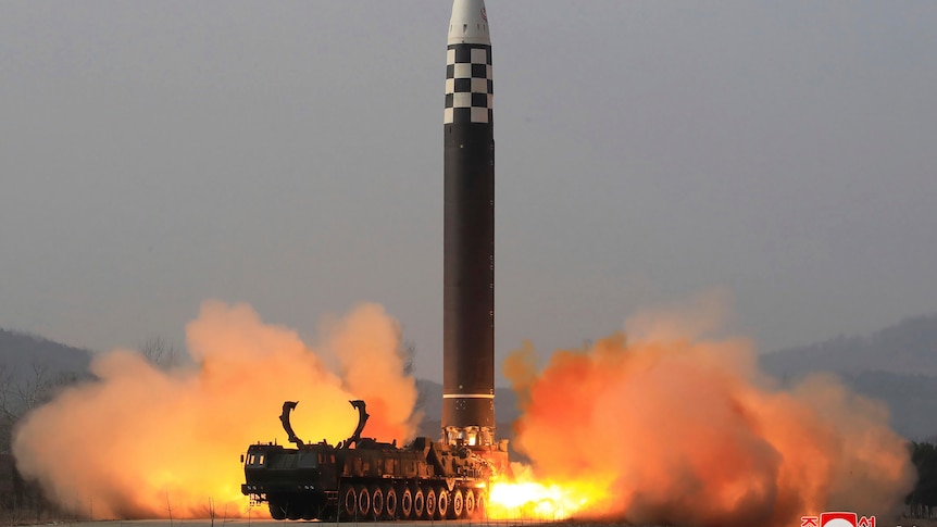 A large intercontinental ballistic missile is lauched vertically  from a truck, with flames from its exhaust hitting the ground.