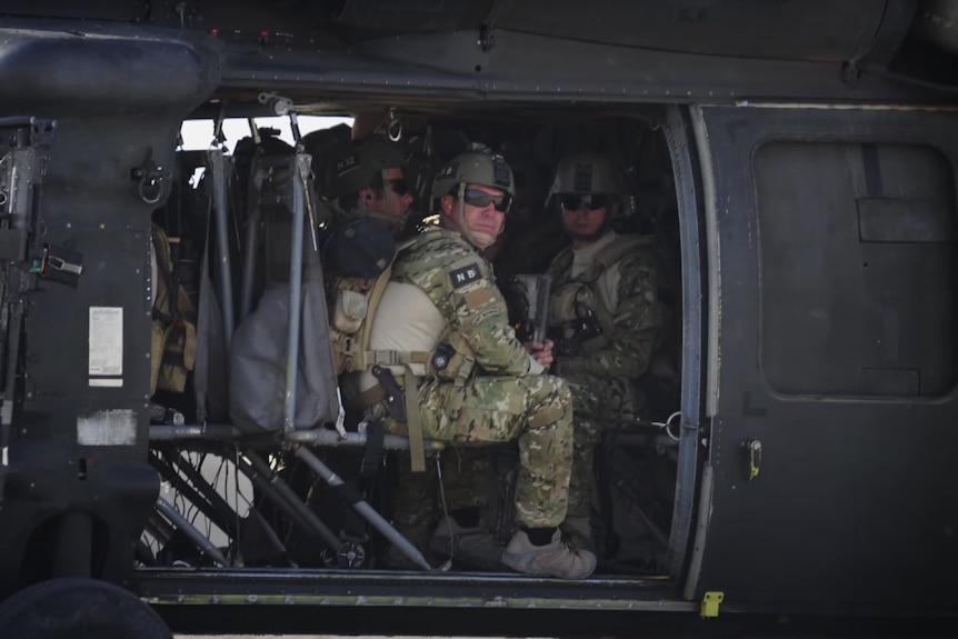 a group of soldiers sitting inside a military helicopter