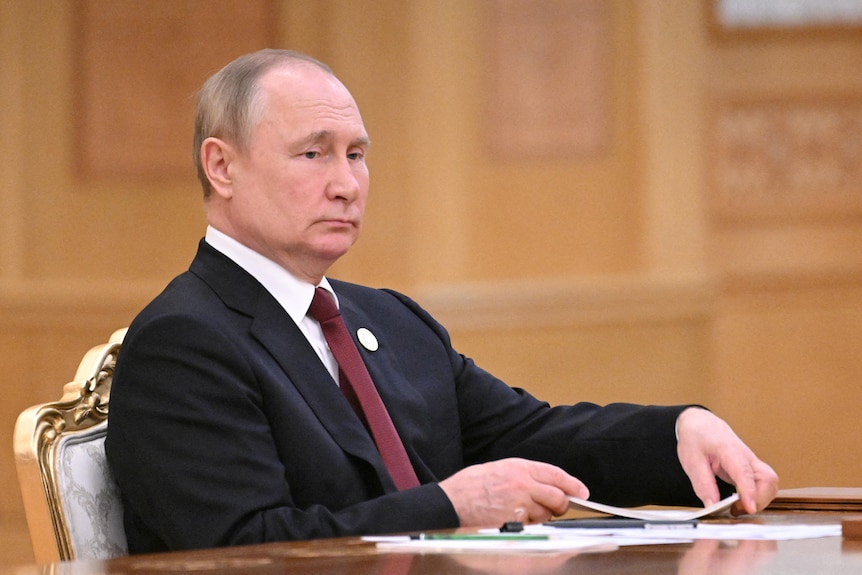 Man in suit sits at table.