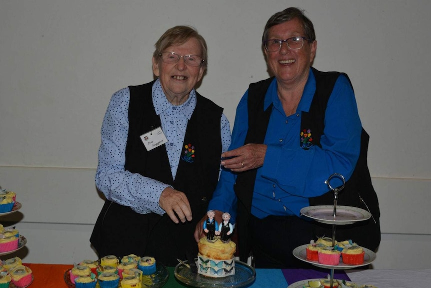 Two women in front of a wedding cake