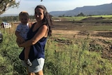 Kembla Grange resident Ami Beck stands at the site of the proposed prison in the Illawarra with her baby.