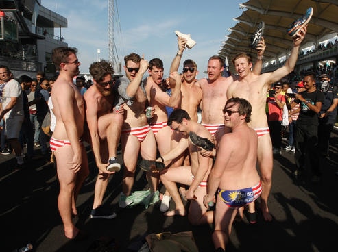 Australian men celebrate in swimwear decorated with the Malaysian flag at the grand prix