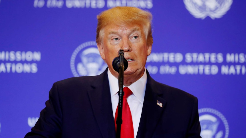 Donald Trump looks to the side as he speaks into a microphone at the United Nations