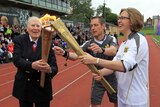 Firming in betting ... Sir Roger Bannister (L) passes the Olympic flame during the torch relay's journey around England