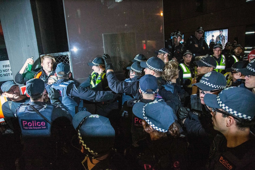 A protester is detained by police on collins street