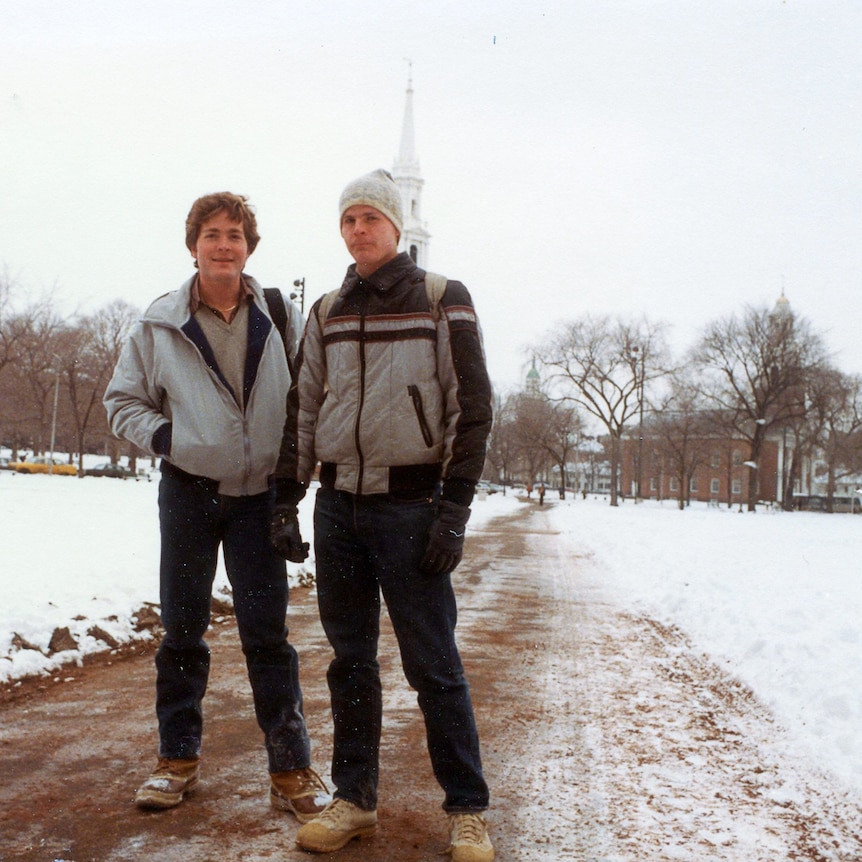 A photo of two men standing on a snowy path wearing warm clothes.