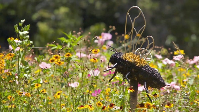Field of flowers with a bee sculpture on a stake