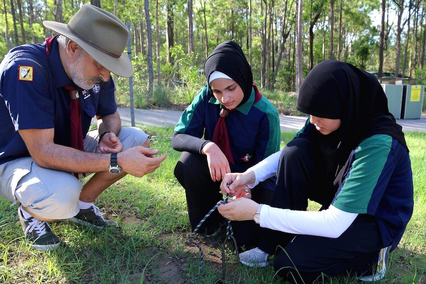 A Scout leader guiding young Scouts in rope-tying