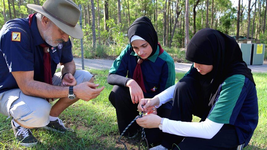 A Scout leader guiding young Scouts in rope-tying