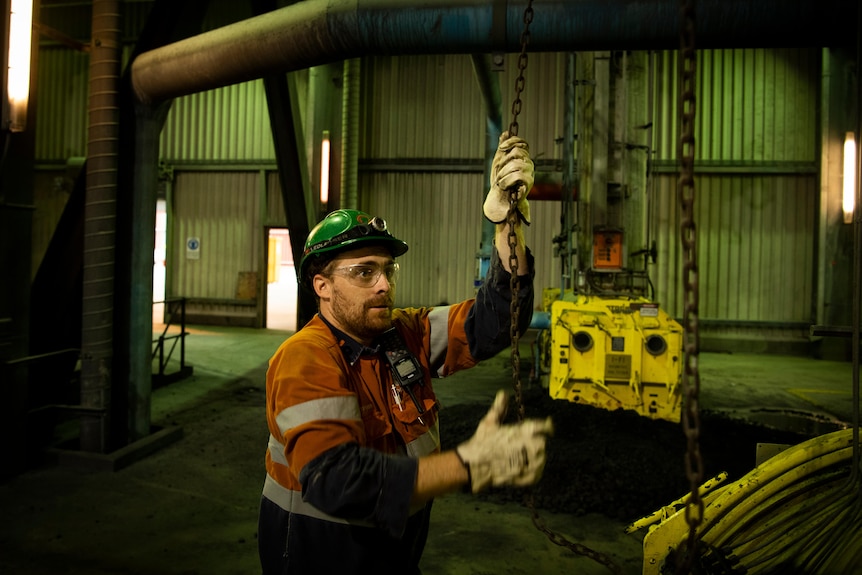 A man pulls down a chain with a hook on it