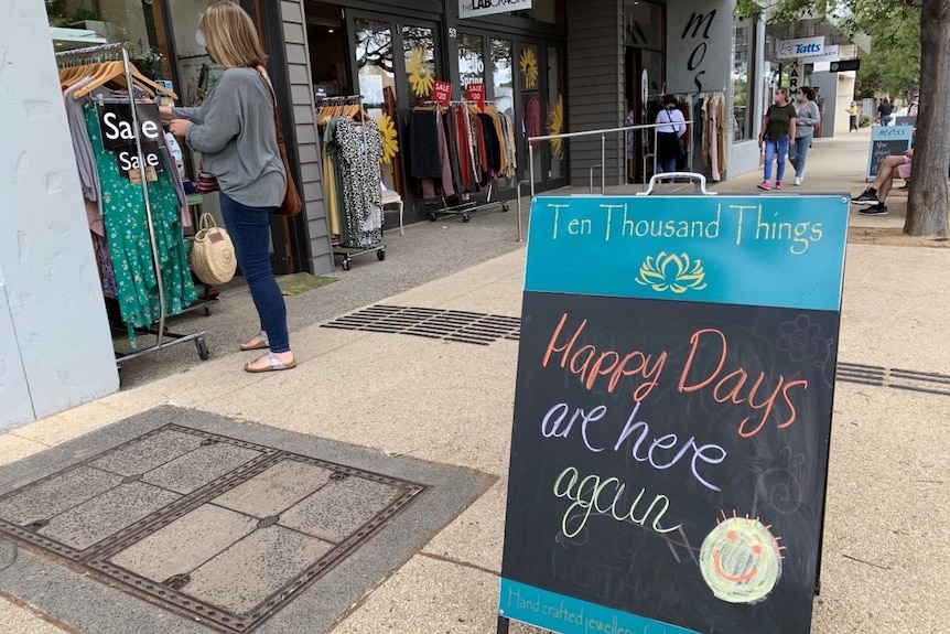 A chalkboard sign outside a clothes shop saying 'happy days are here again'.