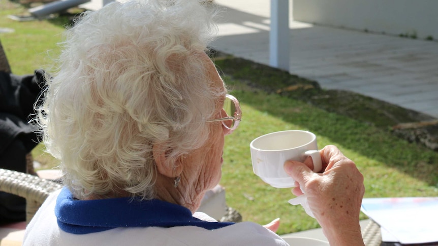 Elderly woman sitting and having a cup of tea.