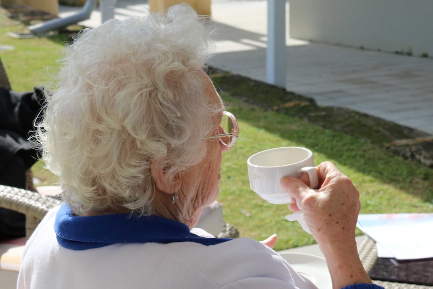 Elderly woman sitting and having a cup of tea.