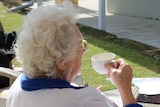 Elderly woman sitting and having a cup of tea.
