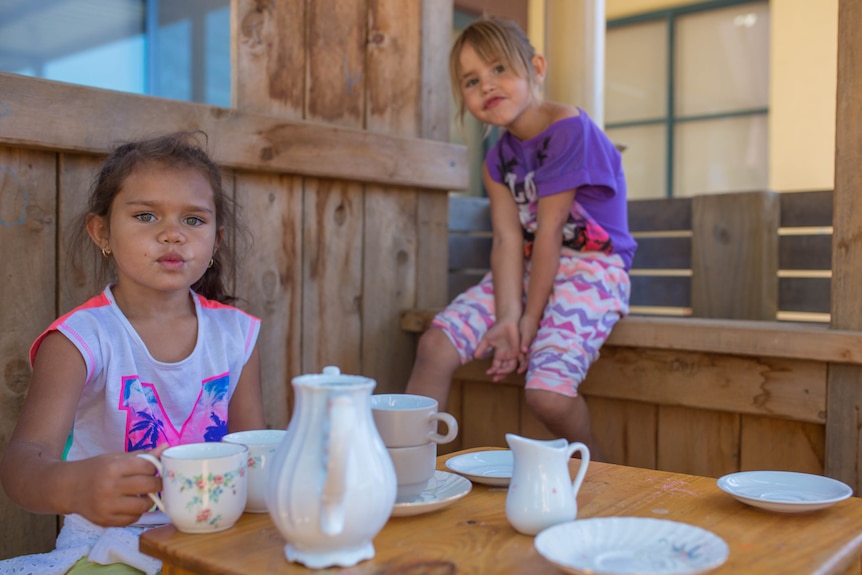 Two girls at Lulla's Children and Family Service in Shepparton play with a tea set in a wooden play house.