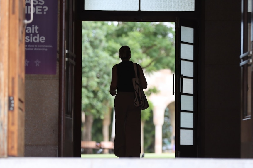 a female student walks through large doors at uq's st lucia campus. her identity is concealed