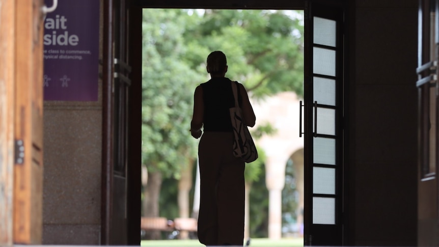 a female student walks through large doors at uq's st lucia campus. her identity is concealed