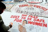 An Indian woman writes on a banner supporting the hanging of the rapists.