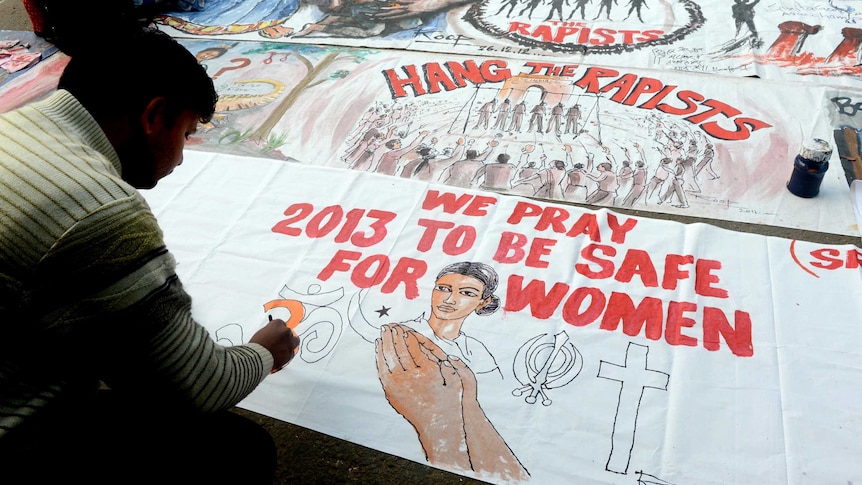 Indian protesters write on a banner supporting the hanging of the accused rapists.