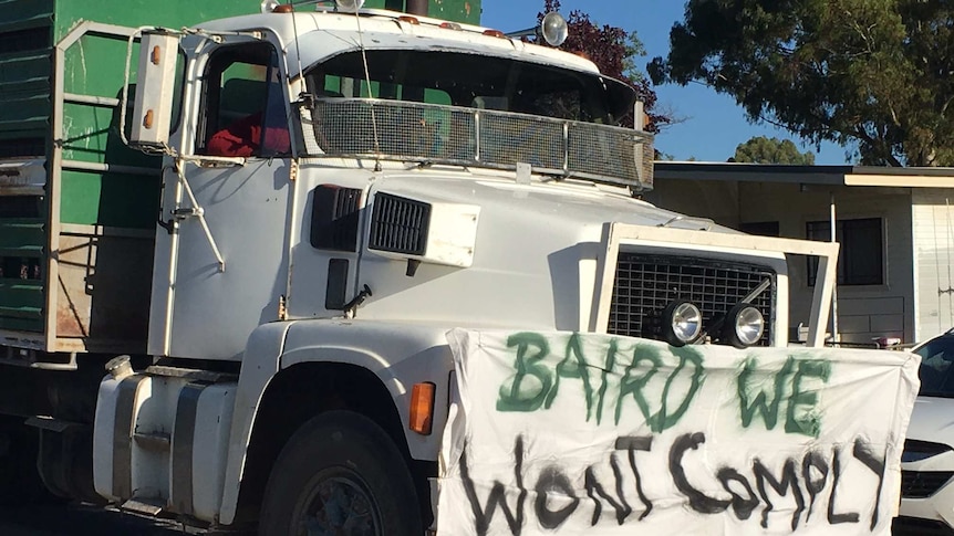 A sign on a semi trailer saying 'Baird we won't comply'