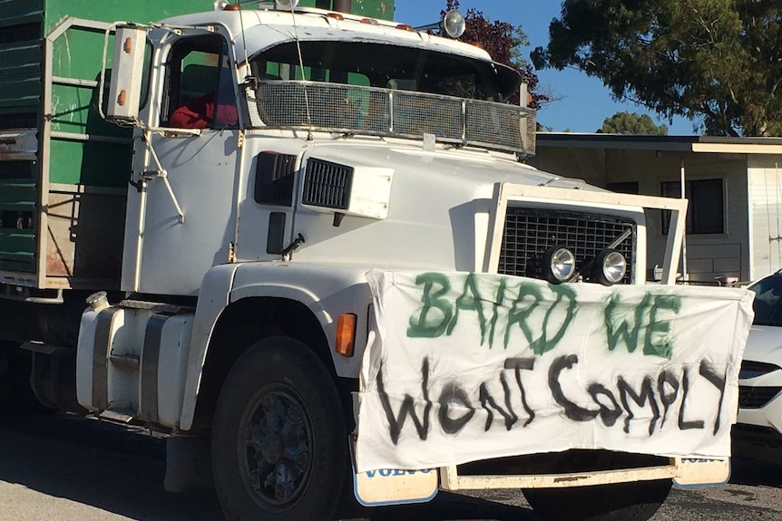 A sign on a semi trailer saying 'Baird we won't comply'