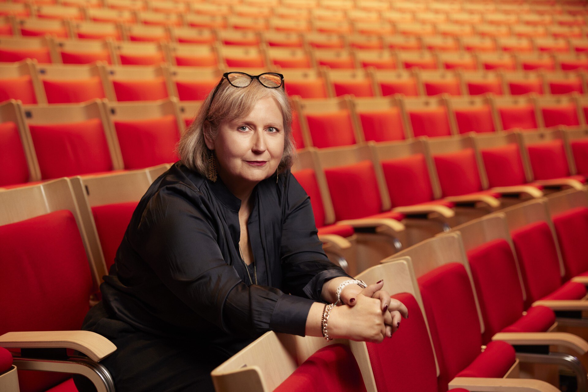 Opera Australia artistic director Jo Davies sits in an audience seat in an empty theatre.