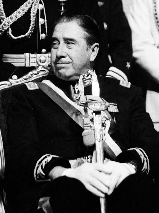 Black and white image of Pinochet sitting in in military clothing.