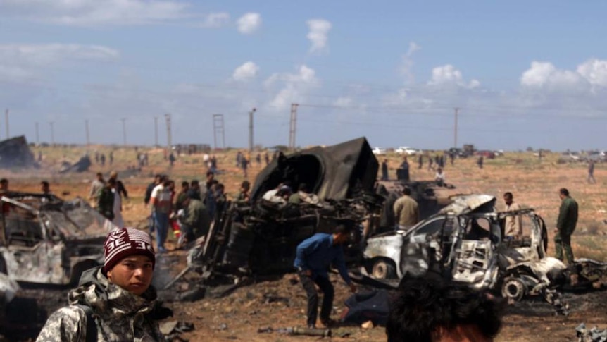 Libyan rebels walk past wrecked military vehicles