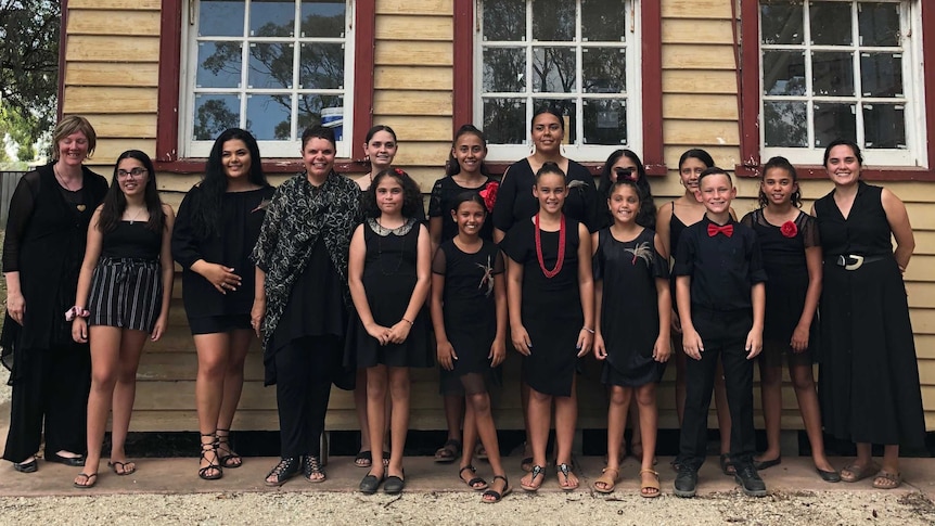 Dhungala Children's Choir standing in front of the old school house