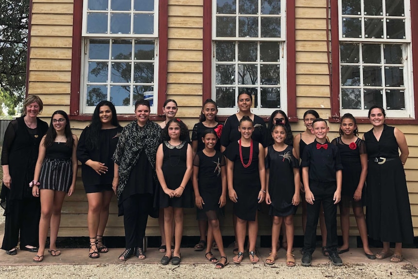 Dhungala Children's Choir standing in front of the old school house