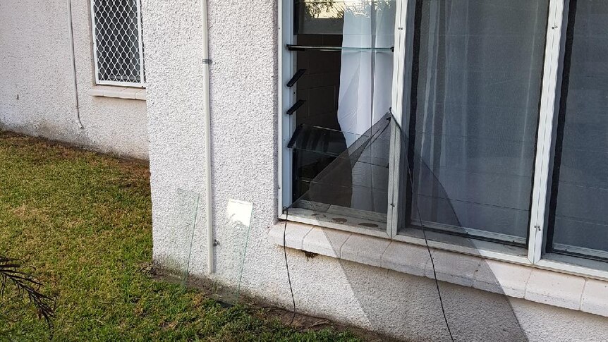 The exterior of a ground-floor unit with a fly screen torn open and glass louvres broken.