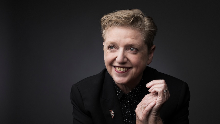 Robyn Archer smiling, on a dark grey background