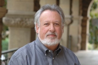 A man wearing a shirt looks at the camera in a close up portrait photo.