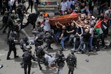 Israeli forces beat mourners carrying a coffin.