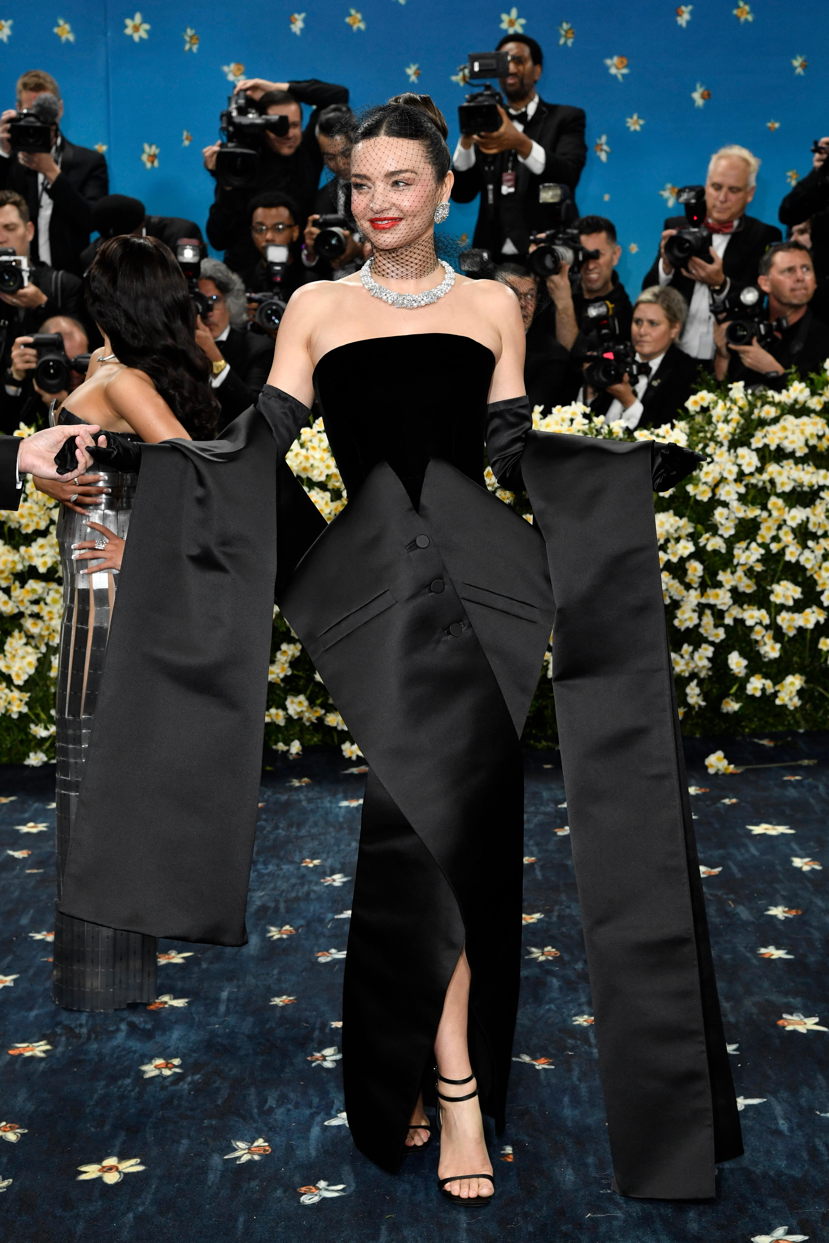 Miranda Kerr wearing a black strapless gown with tuxedo-like detailing that drapes down the skirt