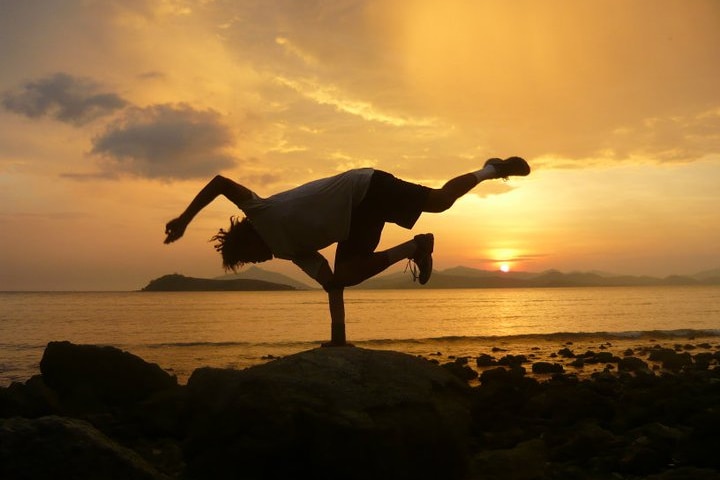 A silhouette of a person breaking with a sunset in the background.
