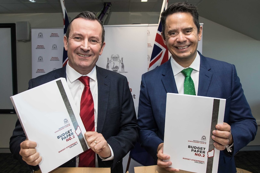 Two men in suits hold copies of the state budget.