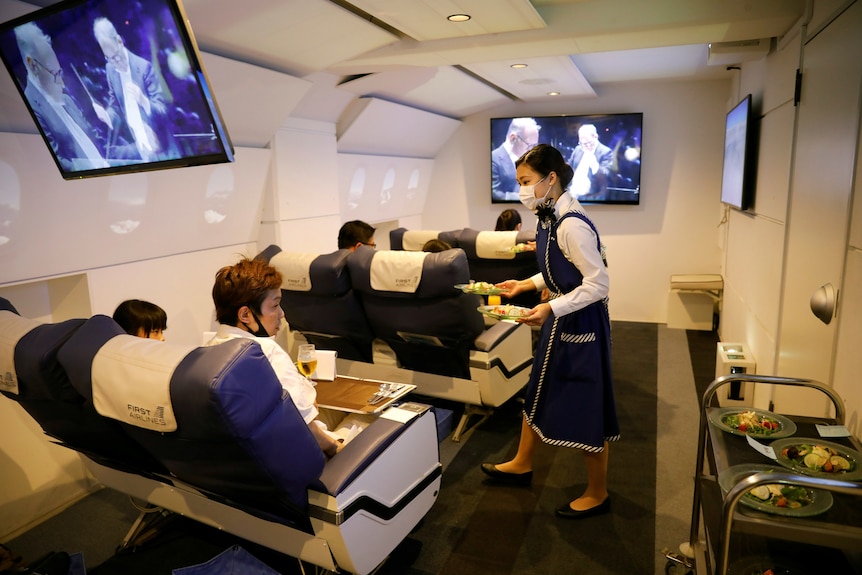Staff dressed as flight attendants serves meals to customers in a fake plane.