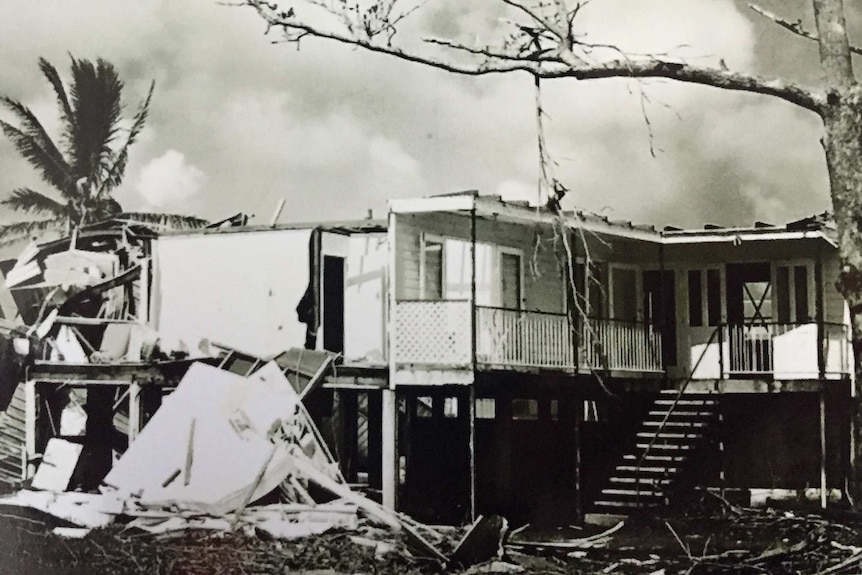 A black and white photograph depicts a house wrecked by Tropical Cyclone Yasi.