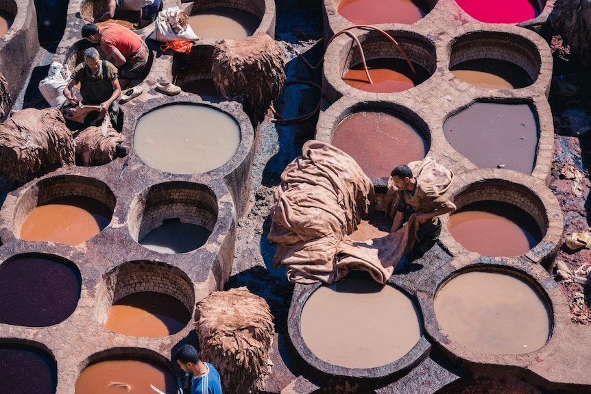 Shot from above of circular pits filled with different coloured liquids.