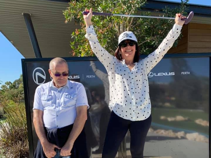 Daniella holds a golf club above her head on a podium and Giacomo is in second place, in front of a lexus brand sign.