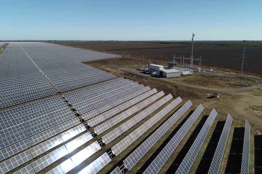 An aerial view showing the large amount of solar panels, with an office that looks small by comparison.