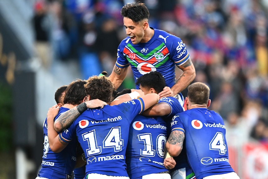 A group of Warriors NRL players embrace as they celebrate a try against the Wests Tigers.