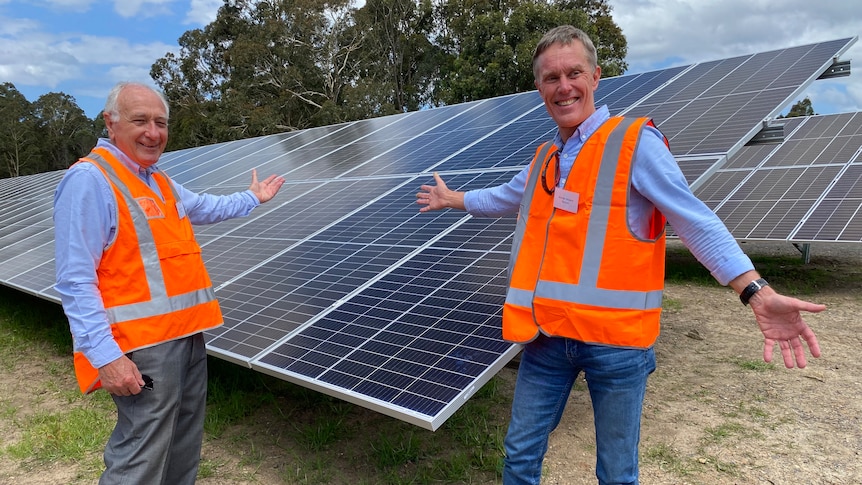 Two men in front of a solar panel